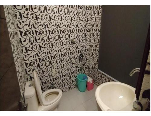 a bathroom with a black and white shower curtain and a toilet at Hotel Atithi, Near Yes Bank, Mall Road, Mussoorie in Mussoorie