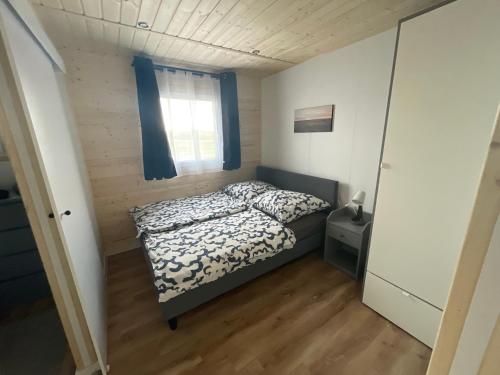 ein kleines Schlafzimmer mit einem Bett und einem Fenster in der Unterkunft TinyHaus #1 Hülben - Ortsrand - kostenlose Parkplätze in Hülben