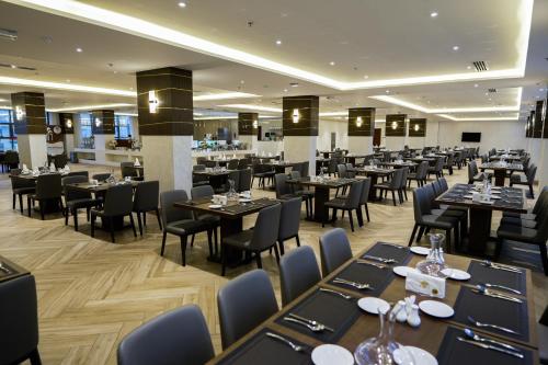 um restaurante com mesas e cadeiras pretas e mesa de trabalho em The Plaza Hotel & Resort em Salalah