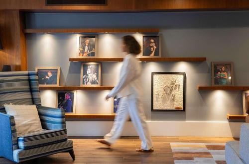 a woman walking in a living room with portraits on the wall at Hyatt Regency Newport Beach in Newport Beach