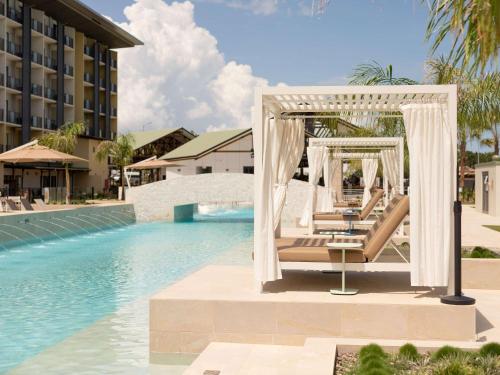 un grupo de tumbonas junto a la piscina en un complejo en Mercure Darwin Airport Resort, en Darwin