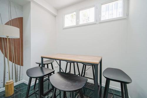 une table et quatre tabourets dans une pièce dans l'établissement Appartement Mairie des Lilas - III, aux Lilas