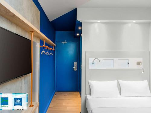 a room with a white bed and a blue wall at ibis budget Amiens Centre Gare in Amiens