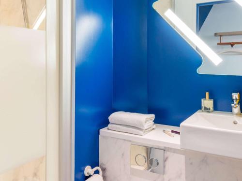 La salle de bains est pourvue de murs bleus et d'un lavabo blanc. dans l'établissement ibis budget Amiens Centre Gare, à Amiens