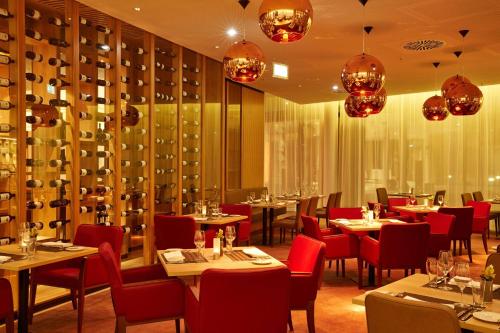 a restaurant with tables and chairs and chandeliers at H4 Hotel München Messe in Munich
