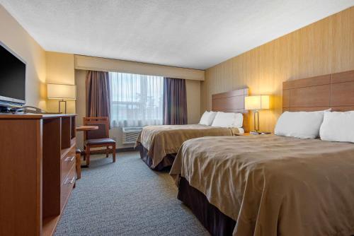 a hotel room with two beds and a television at Quality Inn & Conference Centre Downtown Sudbury in Sudbury