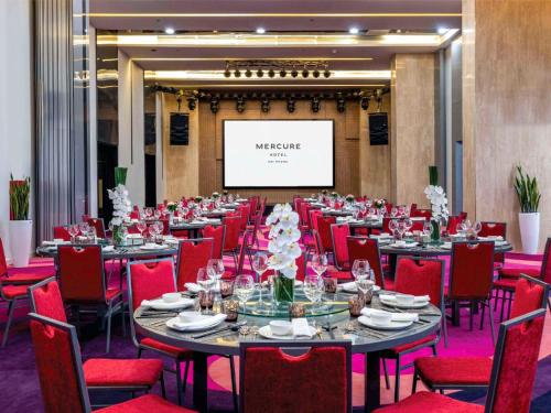 a conference room with tables and red chairs and a screen at Mercure Hai Phong in Hai Phong