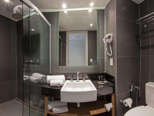 uma casa de banho com um lavatório, um espelho e um WC. em ibis Styles Palmas em Palmas