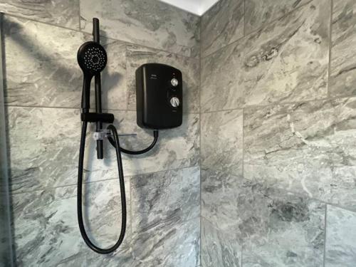 a shower with a phone on the wall in a bathroom at Burmer Central Bliss: Modern 3BR/1BA, Full Kitchen in Peterborough