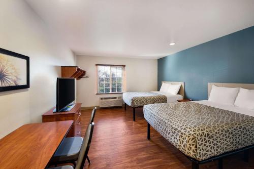Cette chambre comprend deux lits et une télévision. dans l'établissement WoodSpring Suites Columbus Southeast, à Groveport