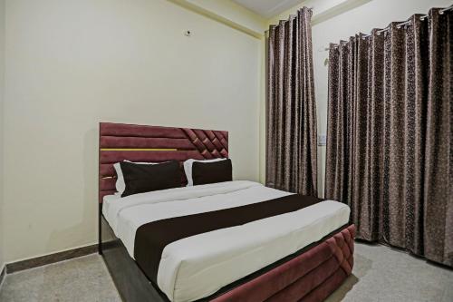 - une chambre avec un grand lit et des rideaux dans l'établissement OYO J M K Hotel, à Gurgaon