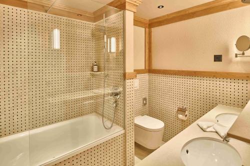 a bathroom with a tub and a toilet and a sink at The Glacier Hotel - ex Eurotel Victoria - in Les Diablerets
