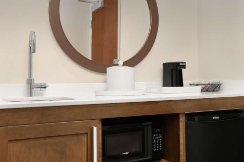 a bathroom with a microwave and a sink and a mirror at Hampton Inn & Suites Durham University Medical Center in Durham