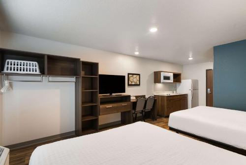 Habitación de hotel con 2 camas y escritorio con TV. en WoodSpring Suites Rockledge - Cocoa Beach en Rockledge