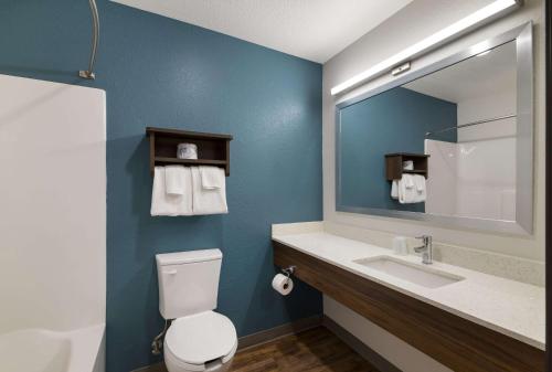 W łazience znajduje się toaleta oraz umywalka z lustrem. w obiekcie WoodSpring Suites Rockledge - Cocoa Beach w mieście Rockledge