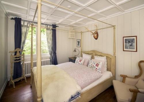 ein Schlafzimmer mit einem Himmelbett und einem Fenster in der Unterkunft B&B Langenberg in Langnau am Albis