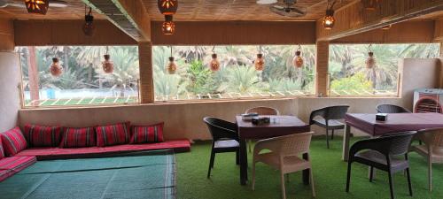 a restaurant with tables and chairs and a large window at Sehma Guest House in Al Ḩamrāʼ