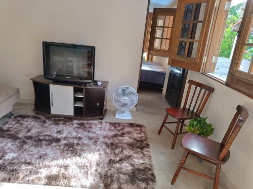 uma sala de estar com uma televisão de ecrã plano e cadeiras em Chácara das Pedras em Taubaté