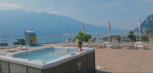 a woman sitting in a hot tub on a deck at Hotel Sogno del Benaco in Limone sul Garda