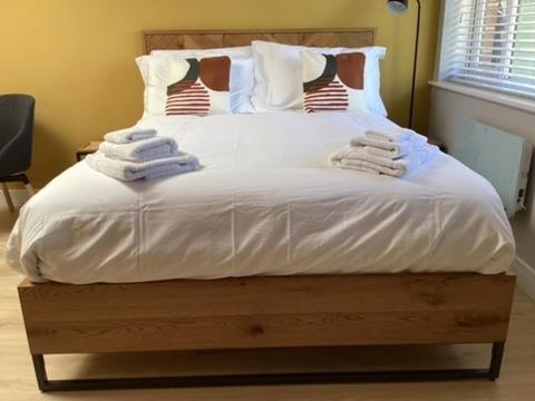 Una cama con sábanas blancas y toallas. en Studio 33, en Chichester