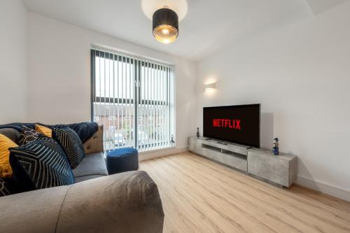 a living room with a couch and a flat screen tv at Modern Stylish 1 bedroom apartment in the heart of Potters Bar in Potters Bar