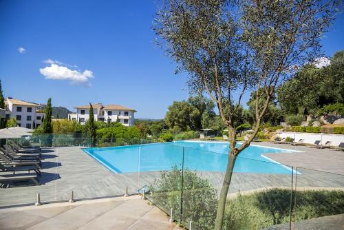 a large swimming pool with chairs and a tree at Domaine d'Arca - Gauguin 12 - 2 chambres - étage 2 in Porto-Vecchio