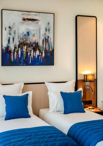 two beds with blue pillows in a hotel room at MIA Mazagan Bay in El Jadida