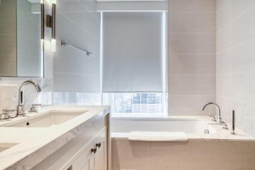 a white bathroom with a tub and a sink at Downtown Luxury - Stunning Burj Khalifa & Sea View - 5 Minutes Walk to Dubai Mall in Dubai