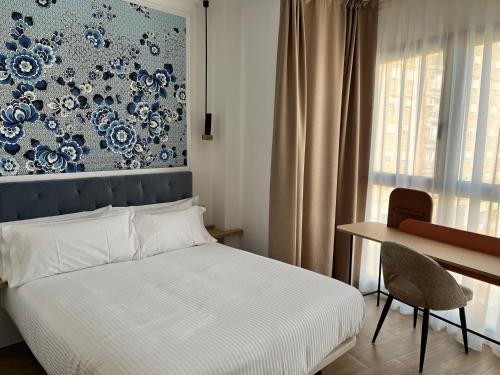 a bedroom with a bed and a desk and a wall at Lumen Mare by SH Hoteles in Valencia