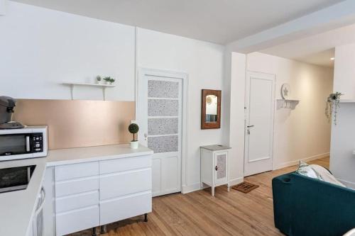 une cuisine avec des placards blancs et un canapé bleu dans l'établissement Cosy Queen - 3CH - Hyper centre & parking, à Pau