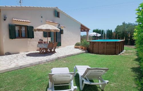a house with two chairs and a table and an umbrella at Villa Can Bolloy Mallorca by PriorityVillas in Llucmajor