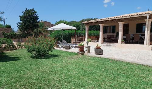 a backyard with an umbrella and a house at Villa Can Bolloy Mallorca by PriorityVillas in Llucmajor