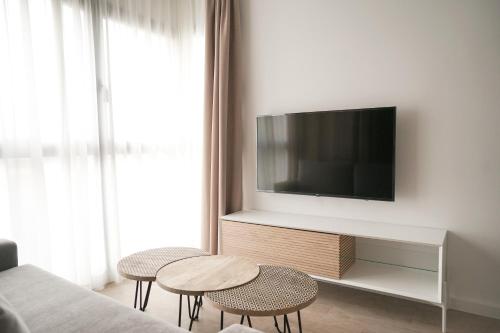 Lumen Mare by SH Hoteles في فالنسيا: غرفة معيشة مع تلفزيون وطاولتين وكراسي