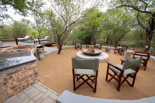 a patio with tables and chairs and a fire pit at Africa House in Hoedspruit