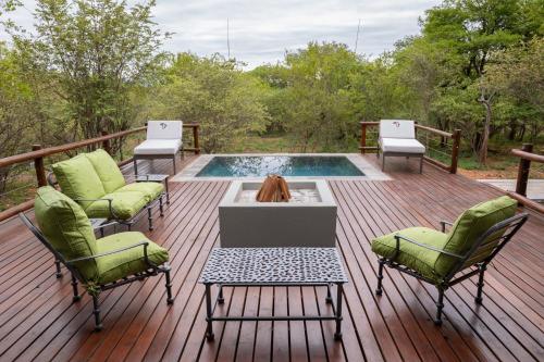 a deck with a pool and chairs and a fire pit at Africa House in Hoedspruit