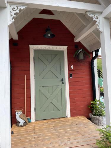a cat sitting on the porch of a red house with a green door at Wioska w Sowich Sokolec in Sokolec