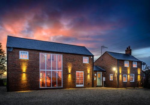 a brick house with a sunset in the background at Immaculate historical 2-Bed Cottage in The Fens in Lutton