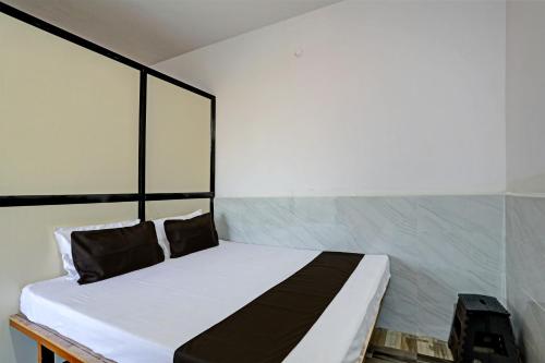 Schlafzimmer mit einem Bett mit weißer Bettwäsche und schwarzen Kissen in der Unterkunft OYO Madhupushpa Farm House in Rāmtek