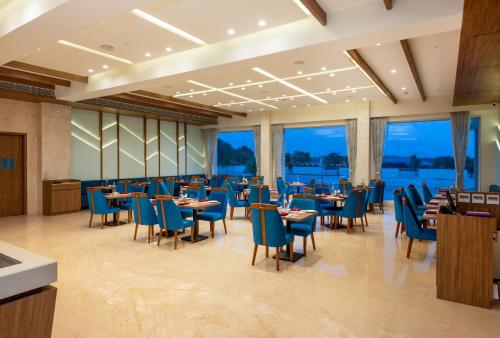 a restaurant with blue chairs and tables and windows at The Orchid Jamnagar in Jamnagar