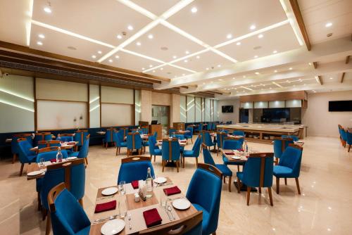 a dining room with tables and blue chairs at The Orchid Jamnagar in Jamnagar
