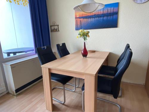 Burgtiefe auf Fehmarn にあるSuedstrand-Ferienwohnung-Suhrのダイニングルームテーブル(椅子付)、花瓶