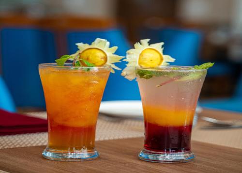 two cocktails sitting on top of a wooden table at The Orchid Jamnagar in Jamnagar