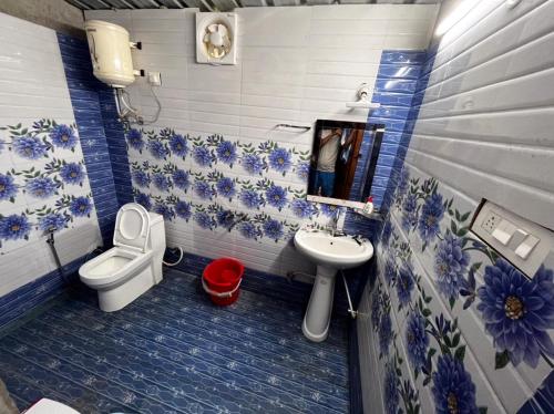 a blue and white bathroom with a toilet and a sink at BUNK CHAMBER in Mukteshwar