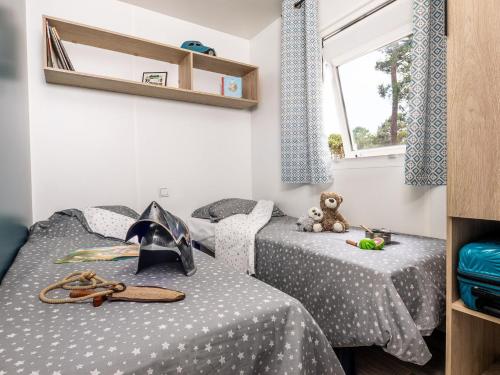 2 Einzelbetten in einem Zimmer mit einem Teddybär in der Unterkunft Camping Arès in Arès