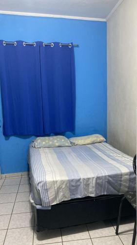 um quarto azul com uma cama com uma parede azul em Kitinete perto da praia e Shopping Brisamar em São Vicente, na Biquinha, temporada e mensal tudo incluso, mobiliado, wi fi, ventilador, elevador, horário flexível em São Vicente