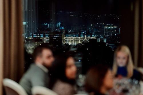 a group of people sitting at a table with a view of the city at Unirea Hotel & Spa in Iaşi