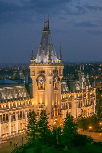 a large building with a clock tower at night at Unirea Hotel & Spa in Iaşi