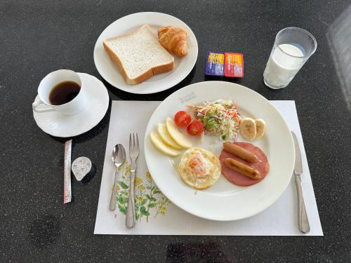 2 Teller mit Frühstückslebensmittel und eine Tasse Kaffee in der Unterkunft Natural Hot Spring Hakuba Symphony in Hakuba