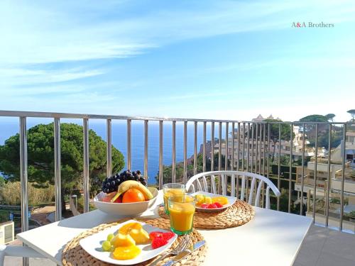 a table with bowls of fruit and drinks on a balcony at A&A Brothers -The Apartments- in S'Agaro
