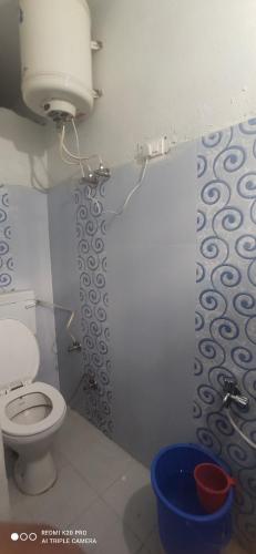 a bathroom with a toilet and a blue bucket at Nitwal Home Stay in Munsyari